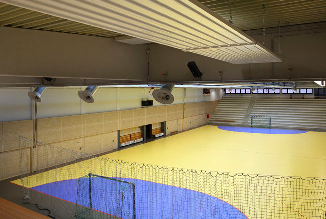 Sporthalle mit an der Decke verbauten Deckenstrahlplatten - fotografiert von der Tribühne aus