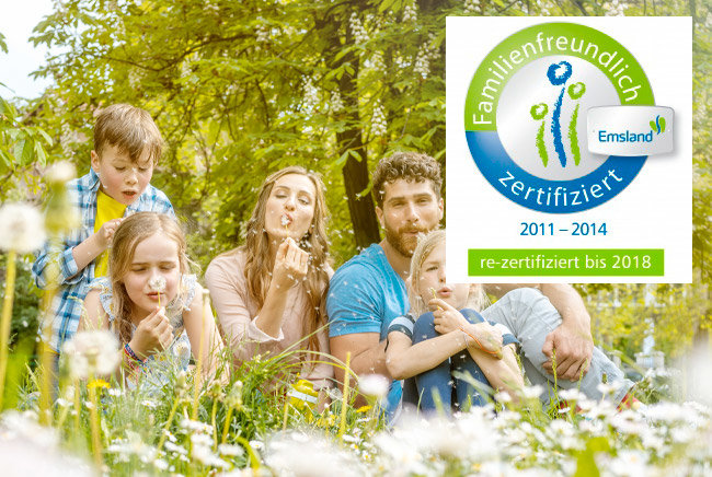 Familie mit 3 Kindern sitzt auf einer Wiese, hält Pusteblumen in der Hand und pustet, darauf das Logo der Zertifizierung